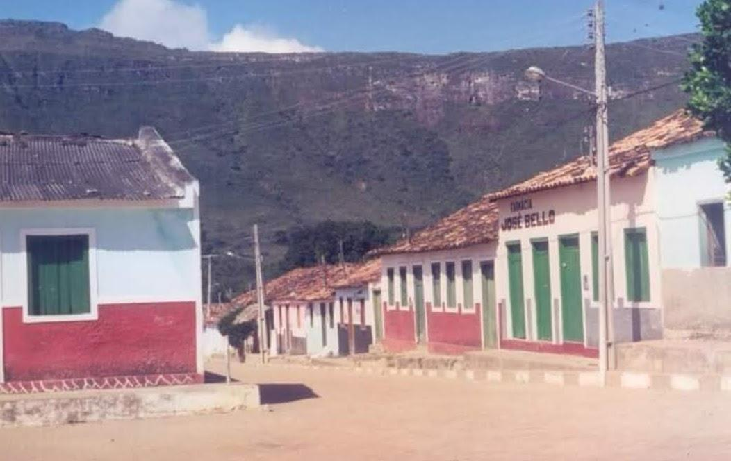 Foto de época de uma rua do Vale do Capão, com casas coloridas e a serra ao fundo